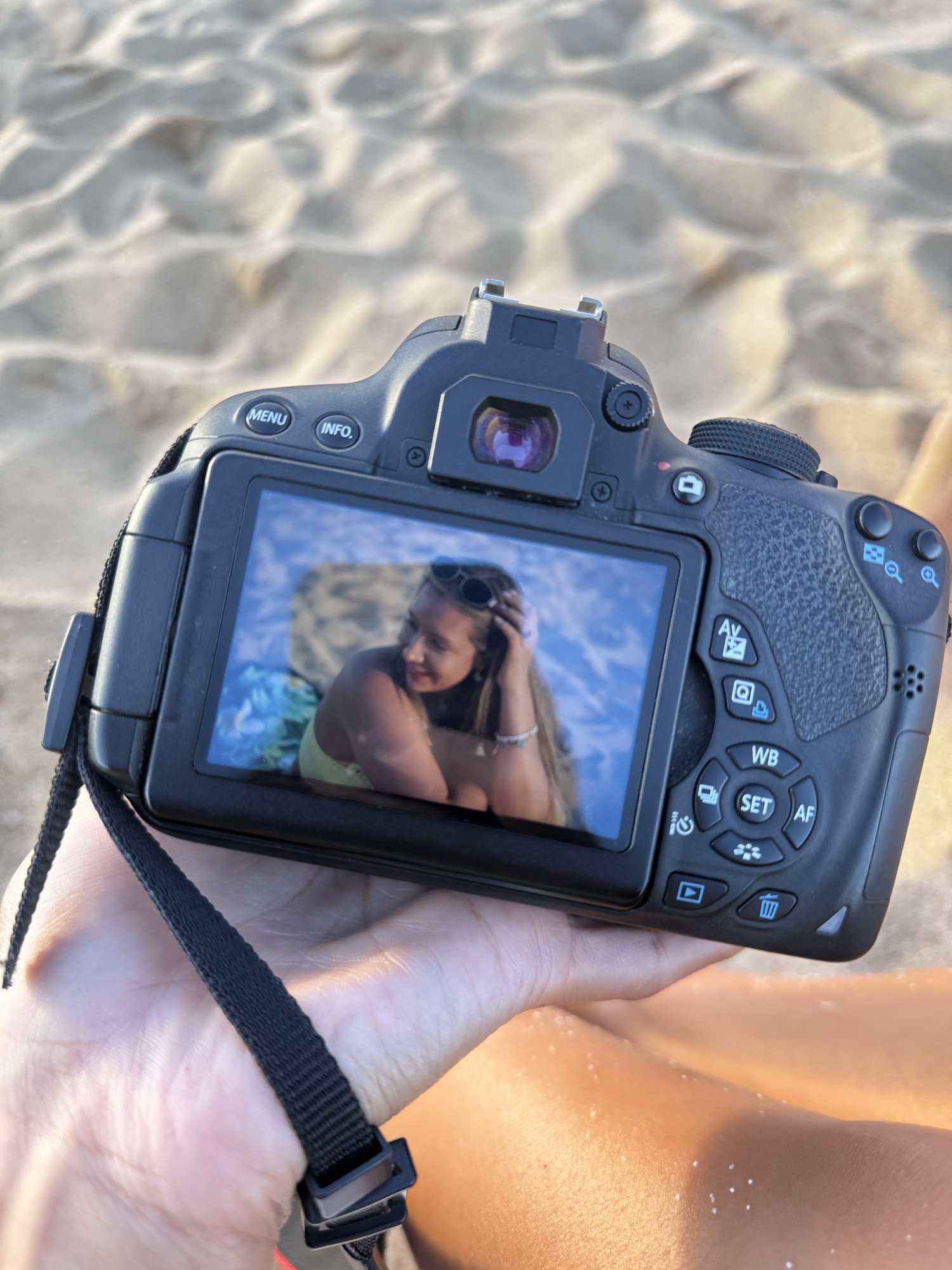 A camera showing a photo of a woman on the beach